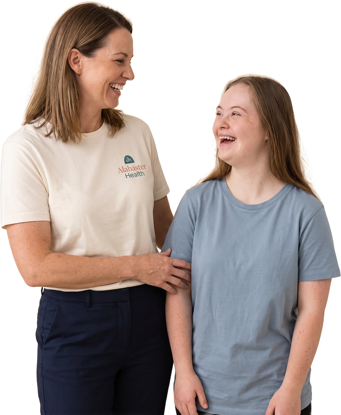 An Alabaster Health support worker in a branded ivory shirt laughing with a young woman with Down syndrome, her hand resting gently on her arm.